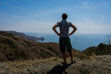 Ayakta ve bech Pasifik Okyanusu'nda, bakan genç adam