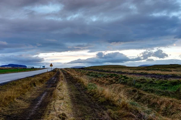 Calle vacía con cielo nublado y paisaje islandés durante Sunr — Foto de Stock