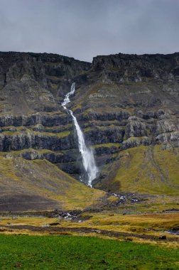 Dağlar ve bulutlu gökyüzü sis ile İzlanda'daki Hegifoss şelale