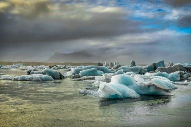 Günbatımı altın saatte glac ile Jokulsarlon içinde yüzen buzdağı