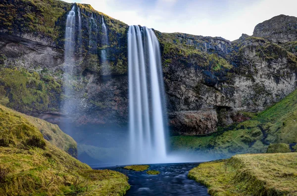 Водопад Seljalandsfoss в Исландии с горами и голубым небом — стоковое фото
