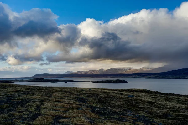 Iceland view over water towards mountains with blue sky and clou