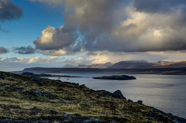 Island view přes vodu směrem k pohoří s modrou oblohu a clou — Stock fotografie