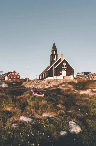 Стара дерев'яна церква в арктичному місті Ілуліссат, з нічним сонцем і синім небом у Північній Гренландії. — стокове фото