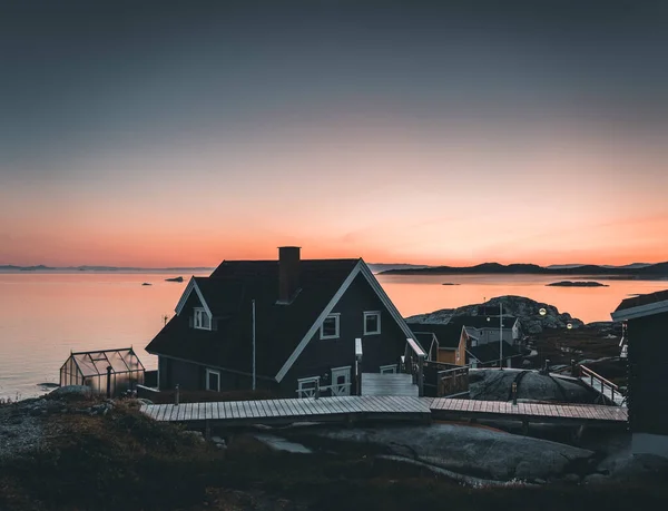 日出日落时，格陵兰的北极城市伊卢利萨的鸟瞰图。五颜六色的房子在镇中心与冰山的背景在夏天的阳光明媚的日子与橙色粉红色的天空 — 图库照片