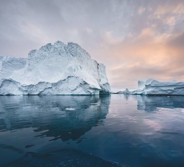 Grönland 'da buzdağlarıyla kutup manzarası gece yarısı güneş batarken ufukta güneş batıyor. Gece yarısı mevsimi boyunca sabah erken saatlerde alpenlight. Ilulissat, Batı Grönland.