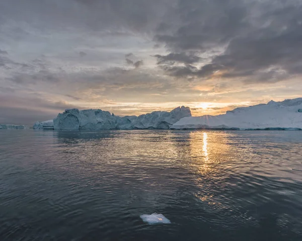 Északi-sarkvidéki táj jéghegyekkel Grönland jéghegyén, éjféli napnyugtakor a láthatáron. Kora reggeli alpenglow az éjféli szezonban. Ilulissat, Nyugat-Grönland. — Stock Fotó