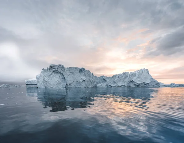 Arktiskt naturlandskap med isberg i Grönlands isfjorden med midnattssoluppgång i horisonten. Tidig försommar alpenglow under midnattssäsongen. Ilulissat, västra Grönland. — Stockfoto