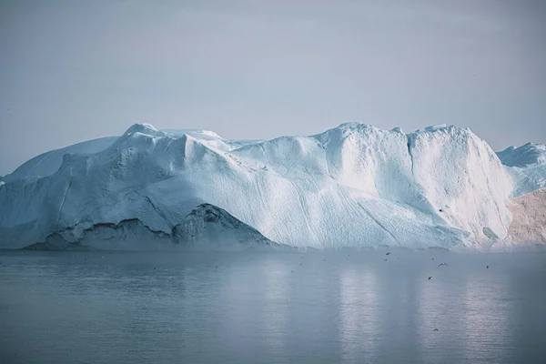 Icebergs varados en la niebla en la boca del fiordo helado cerca de Ilulissat. Naturaleza y paisajes de Groenlandia. Viaje en el barco entre los hielos. Fenómeno del calentamiento global. Costa en la puesta del sol. —  Fotos de Stock