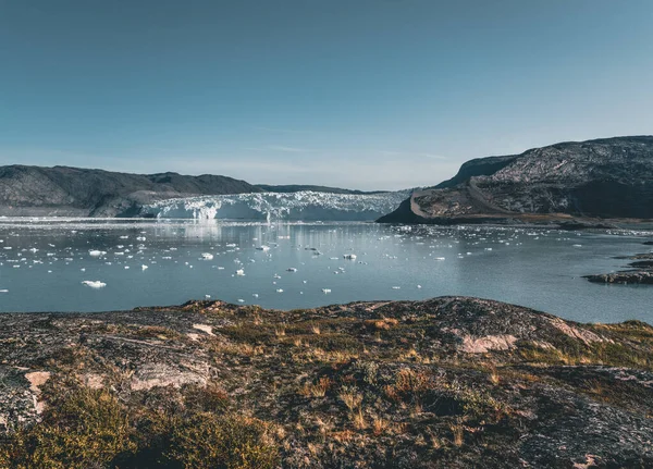 Lodowiec Grenlandzki z lodem morskim i krajobraz lodowcowy w pobliżu lodowca Eqip Sermia, Eqi w zachodniej Grenlandii w pobliżu arktycznego miasta Ilulissat. Błękitne niebo w słoneczny dzień. Lodowiec cielęcy. — Zdjęcie stockowe