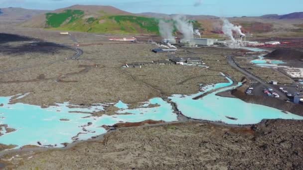 4k Luftdrohne Dampf aus der blauen Lagune, Islands berühmteste heiße Quellen in einem alten Lavafeld verloren, mit einem Vulkan im Hintergrund. — Stockvideo