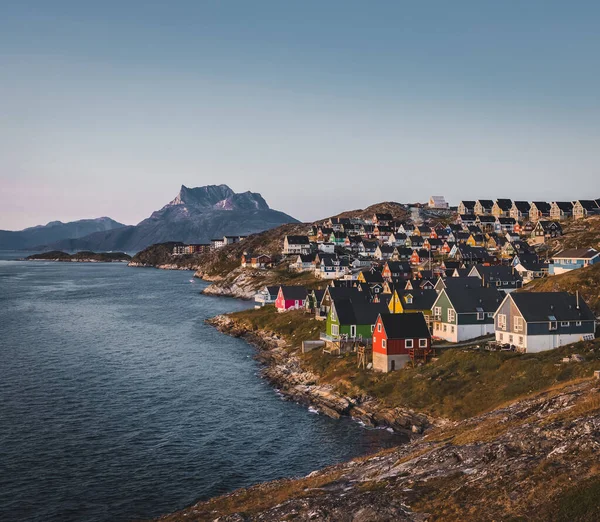 해질 녘의 태양 이 아름답고 다채 로운 색깔의 작은 집들이 있는 그린란드 의수 도인 누크는 아름다운 수도다. 산을 배경으로 하고 있다. 푸른 하늘 과 분홍빛 하늘. — 스톡 사진