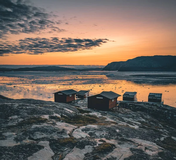 Naturlandschaft grönländischer Gletscher mit berühmten Eqi-Gletschern und Lodge-Hütten. Mitternachtssonne und rosa Himmel. Touristenziel eqi Gletscher in Westgrönland aka ilulissat und jakobshavn Gletscher. Schwerer Unfall — Stockfoto