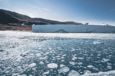 Derin mavi okyanus suyunda yüzen dev bir buzdağı. Grönland ve Antarktika, Ilulissat yakınlarında. Küresel ısınma kavramı. Mavi Gökyüzü ve Buz fiyortu.