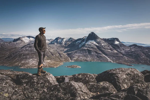Gezonde jongeman gelukkige reiziger toerist staat op de top van een rots hoog in de bergen, genieten van de natuurlijke schoonheid in het ochtendlicht. Scandinavië en Arctische achtergrond met sneeuw en gletsjer — Stockfoto