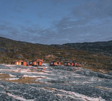 Grönland 'daki Eqip Sermia Buzulu' ndaki Eqi Kampı 'nın panoramik görüntüsü. Kulübeleri olan doğa manzarası. Gece yarısı güneşi ve pembe gökyüzü. Batı Grönland 'daki Eqi buzulu, nam-ı diğer Ilulissat ve