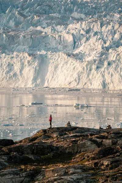 Mensen die voor een enorme gletsjermuur van ijs zitten. Eqip Sermia Gletsjer Eqi gletsjer in Groenland wordt de kalvende gletsjer genoemd tijdens middernachtzon. Wandelaars tijdens reis en vakantie. — Stockfoto