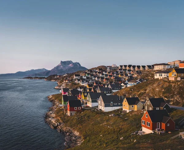 해질 녘의 태양 이 아름답고 다채 로운 색깔의 작은 집들이 있는 그린란드 의수 도인 누크는 아름다운 수도다. 산을 배경으로 하고 있다. 푸른 하늘 과 분홍빛 하늘. — 스톡 사진