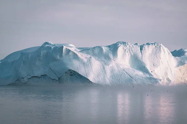 IJsberg bij zonsondergang. Natuur en landschappen van Groenland. Disko baai. West-Groenland. Zomer Middernacht zon en ijsbergen. Groot blauw ijs in de ijskast. Beïnvloed door klimaatverandering en de opwarming van de aarde. — Stockfoto