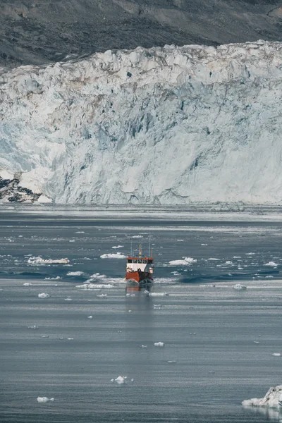 Crucero de pasajeros rojo navegando a través de las aguas heladas de Qasigiannguit, Groenlandia con el glaciar Eqip Sermia Eqi en segundo plano. Un pequeño barco entre icebergs. Velero de crucero entre icebergs flotantes — Foto de Stock
