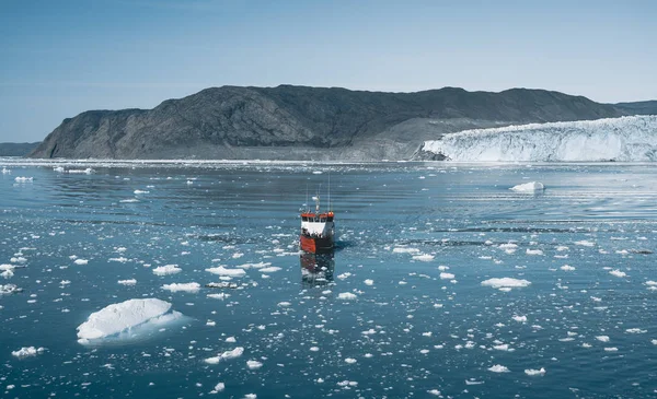 Crucero de pasajeros rojo navegando a través de las aguas heladas de Qasigiannguit, Groenlandia con el glaciar Eqip Sermia Eqi en segundo plano. Un pequeño barco entre icebergs. Velero de crucero entre icebergs flotantes — Foto de Stock