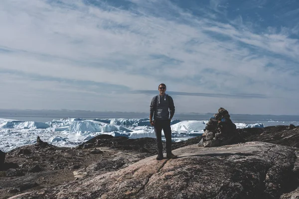 Fiatal utazó turista ül előtt hatalmas gleccser fal jég. Icefjord Ilulissat. Jakobshaven Eqip Sermia Glacier Eqi gleccser Grönlandon, az úgynevezett borjú gleccser éjfélkor — Stock Fotó