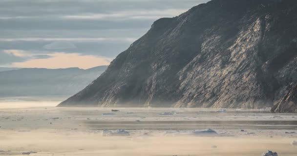 4k移動時間経過グリーンランドのイルリサット近くのアイスフィヨルドの口の霧の中で、鎖状の氷山のビデオクリップ。日の出日の入り時間真夜中の太陽とピンクの空. — ストック動画