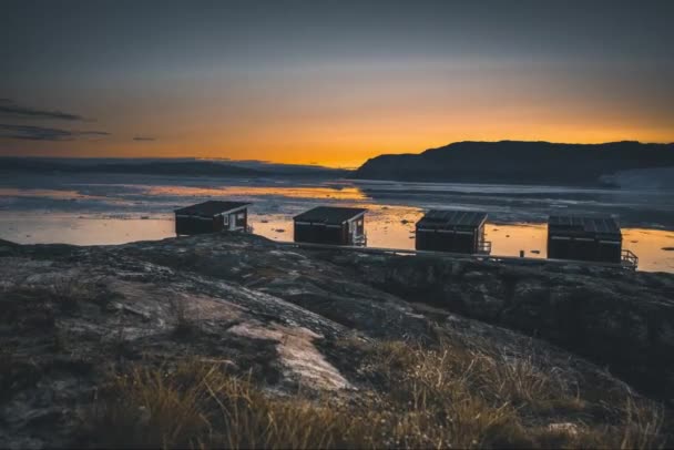 4k liikkuvat Timelapse videoleike Eqip Sermia Glacier Eqi jäätikkö mökit Grönlannissa nimeltään poikiva jäätikkö päivällä sininen taivas ja aurinko. Valtava jäätikköseinä. Suuret jääpalat putoavat — kuvapankkivideo