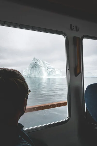 Turista Při pohledu na ledovce a ledovce hory na lodi v západní Grónsku. Ledovec v moři a oceánu. Zataženo. Muž cestovatel. — Stock fotografie