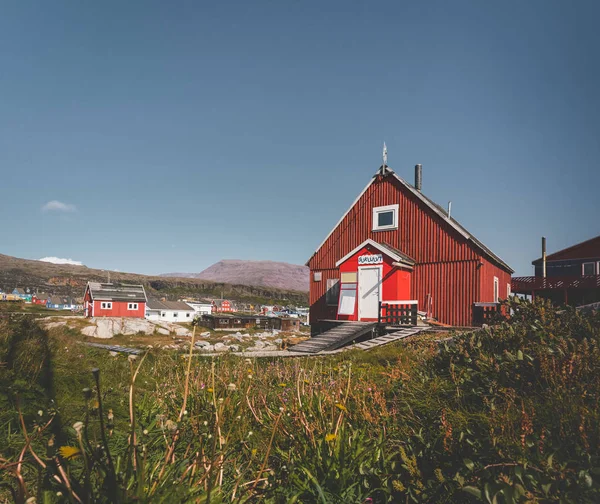 Вид на красочные теплицы острова Диско, арктический город Кекертарсуак. Лодыгин в заливе Фалло. Голубое небо и солнечный день. Столовые горы в фоновом режиме . — стоковое фото
