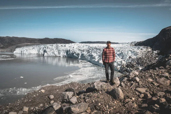 Egy fiatal utazó turista áll az Eqip Sermia gleccser, az Eqi gleccser előtt. Jégfal a háttérben. A globális felmelegedés fogalma és szakmai útmutatók. Egy napsütéses napon, kék égbolttal — Stock Fotó