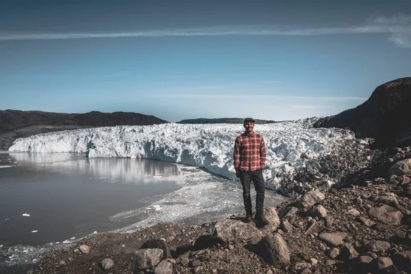 Un joven turista viajero de pie frente al glaciar Eqip Sermia llamado Glaciar Eqi. Pared de hielo en el fondo. El concepto de calentamiento global y guías profesionales. En un día soleado con cielo azul —  Fotos de Stock