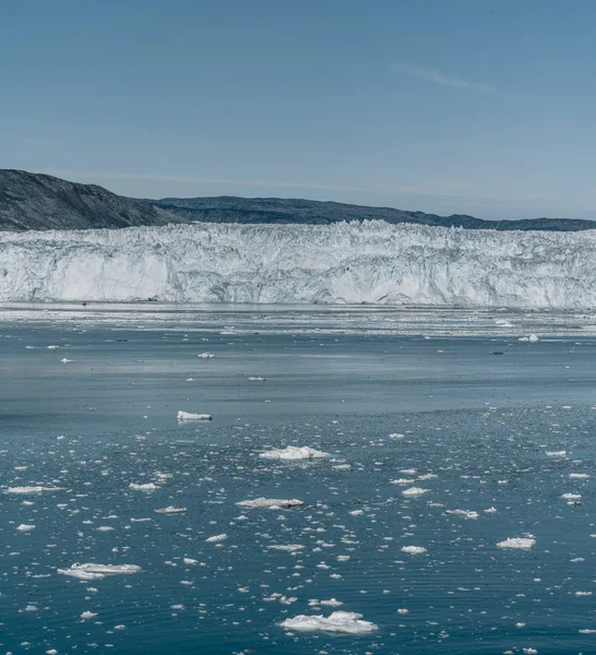 Crucero de pasajeros rojo navegando a través de las aguas heladas de Qasigiannguit, Groenlandia con el glaciar Eqip Sermia Eqi en segundo plano. Un pequeño barco entre icebergs. Velero de crucero entre icebergs flotantes —  Fotos de Stock