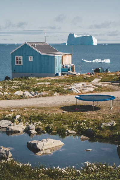 Typical wooden colourful fisher house with iceberg in Qeqertarsuaq, Disko bay area Greenland and Ilulissat. Typical architecture in the arctic circle. Summer and blue sky. — 스톡 사진