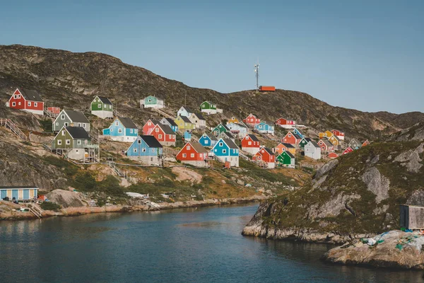 Casele colorate punctează dealurile orașului pescăresc Kangaamiut, Groenlanda de Vest. Iceberguri din ghețarul Kangia din Groenlanda înot cu cerul albastru și nori. Simbolul încălzirii globale . — Fotografie, imagine de stoc