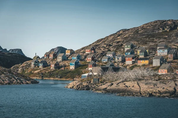 На схилах пагорбів у рибальському місті Кангааміут (Західна Гренландія) стоять барвисті будинки. Айсберги з льодовика Канджа в Гренландії плавають з блакитним небом і хмарами. Символ глобального потепління. — стокове фото