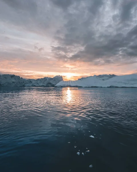 Északi-sarkvidéki táj jéghegyekkel Grönland jéghegyén, éjféli napnyugtakor a láthatáron. Kora reggeli alpenglow az éjféli szezonban. Ilulissat, Nyugat-Grönland. — Stock Fotó