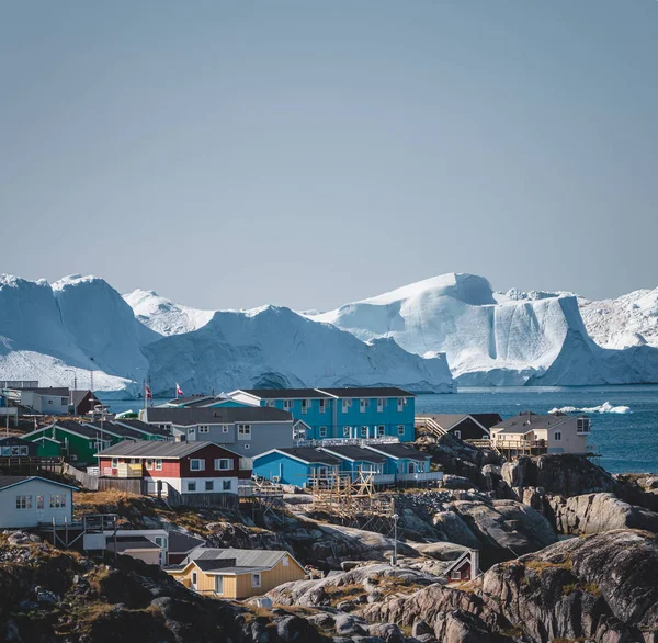 Vista aérea de la ciudad ártica de Ilulissat, Groenlandia. Casas coloridas en el centro de la ciudad con icebergs en el fondo en verano en un día soleado con cielo azul y nubes —  Fotos de Stock