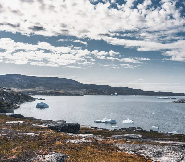 格陵兰岛北冰洋奇形怪状的背斜和景观。 冰山在水里游泳。 夏日的蓝天. — 图库照片
