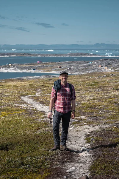 Jongeman toerist voor de ijsberg. Uitzicht op Icefjord in Ilulissat. IJsbergen van Kangia gletsjer in Groenland zwemmen met blauwe lucht en wolken. Symbool van opwarming van de aarde. — Stockfoto