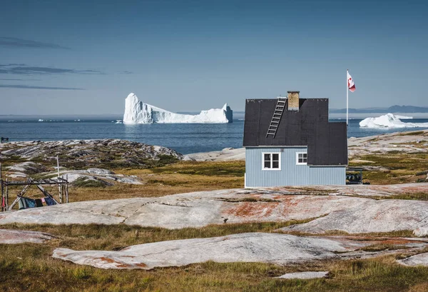 Типовий дерев'яний будинок блакитного рибалочка з айсбергом в районі затоки Діско Гренландія і Ілуліссат. Типова архітектура в арктичному колі. Літо і блакитне небо. — стокове фото