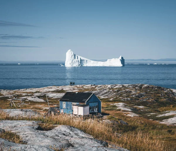 Типовий дерев'яний будинок блакитного рибалочка з айсбергом в районі затоки Діско Гренландія і Ілуліссат. Типова архітектура в арктичному колі. Літо і блакитне небо. — стокове фото