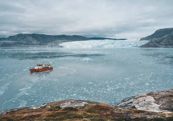 Bateau de croisière à passagers rouge naviguant dans les eaux glacées de Qasigiannguit, Groenland avec le glacier Eqip Sermia Eqi en arrière-plan. Glace se détachant du glacier en vêlage. Un petit bateau parmi les icebergs — Photo