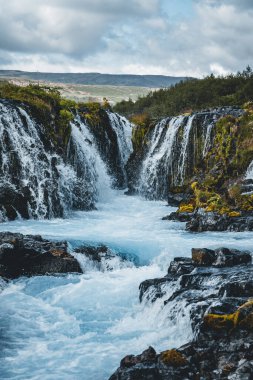 Güçlü Bruarfoss şelalesinin dramatik manzarası. Popüler turist eğlencesi. Gece yarısı güneşi altında mavi gökyüzü ve bulutlar. Konum yeri Brekkuskogur Güney İzlanda, Avrupa.