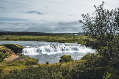 Faxafoss Faxi şelalesi Güney İzlanda 'da patika yolu ile çekilmiş. Su, gece yarısı güneşi altında Altın Daire 'ye dökülüyor. Geniş açı sahnesi.