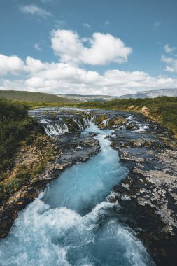 Bruarfoss Şelalesi 'nin inanılmaz manzarası. İzlanda 'nın En Mavi Şelalesi. Mavi su taşların üzerinden akar. İzlanda 'nın gece yarısı güneşi. İzlanda 'yı ziyaret et. Güzellik dünyası.