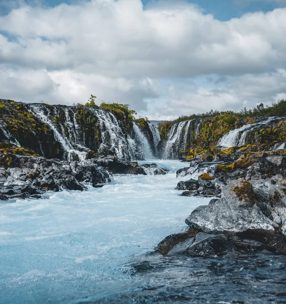 Dramatic views of the bright powerful Bruarfoss bluw waterfall. Popular tourist attraction. Blue sky and clouds during midnight sun. Location place Brekkuskogur South Iceland, Europe. — Stock Photo, Image