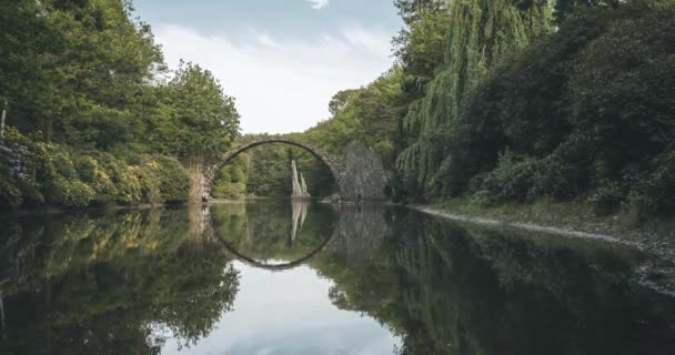 4k bergerak Timelapse Video klip jembatan Rakotz disebut setan jembatan di Kromlau, Saxony, Jerman. Efek cahaya dengan pohon-pohon berwarna-warni dan awan. — Stok Video