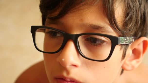 El chico con gafas mira a la distancia. sus ojos se mueven. 4k primer plano. En cámara lenta. espacio de copia — Vídeo de stock