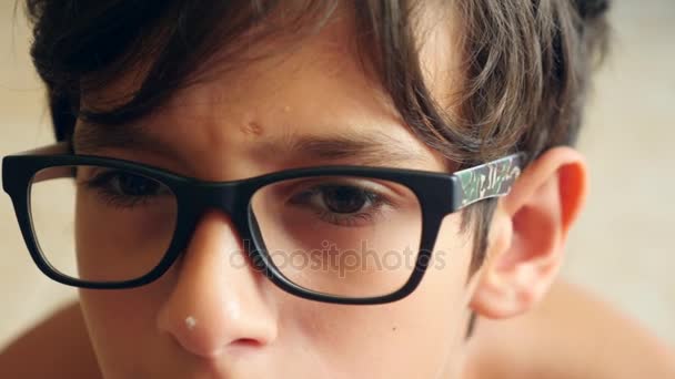 Мальчик в очках смотрит вдаль. Его глаза двигаются. 4К крупным планом. Медленное движение. копировальное пространство — стоковое видео